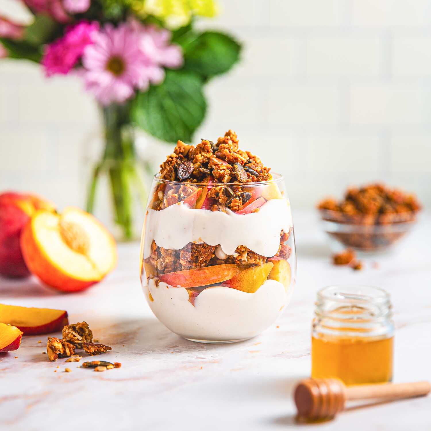 granola in parfait cup with peaches and honey