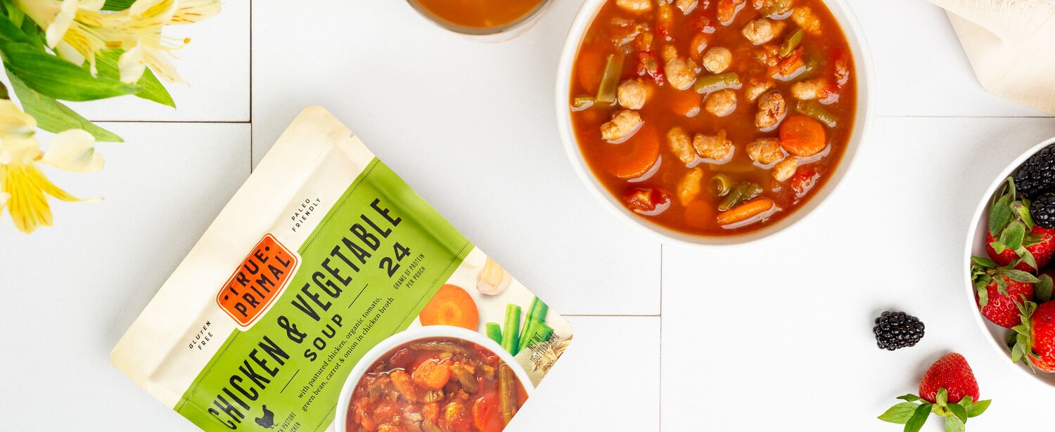 True Primal Chicken & Vegetable Soup in bowl next to pouch