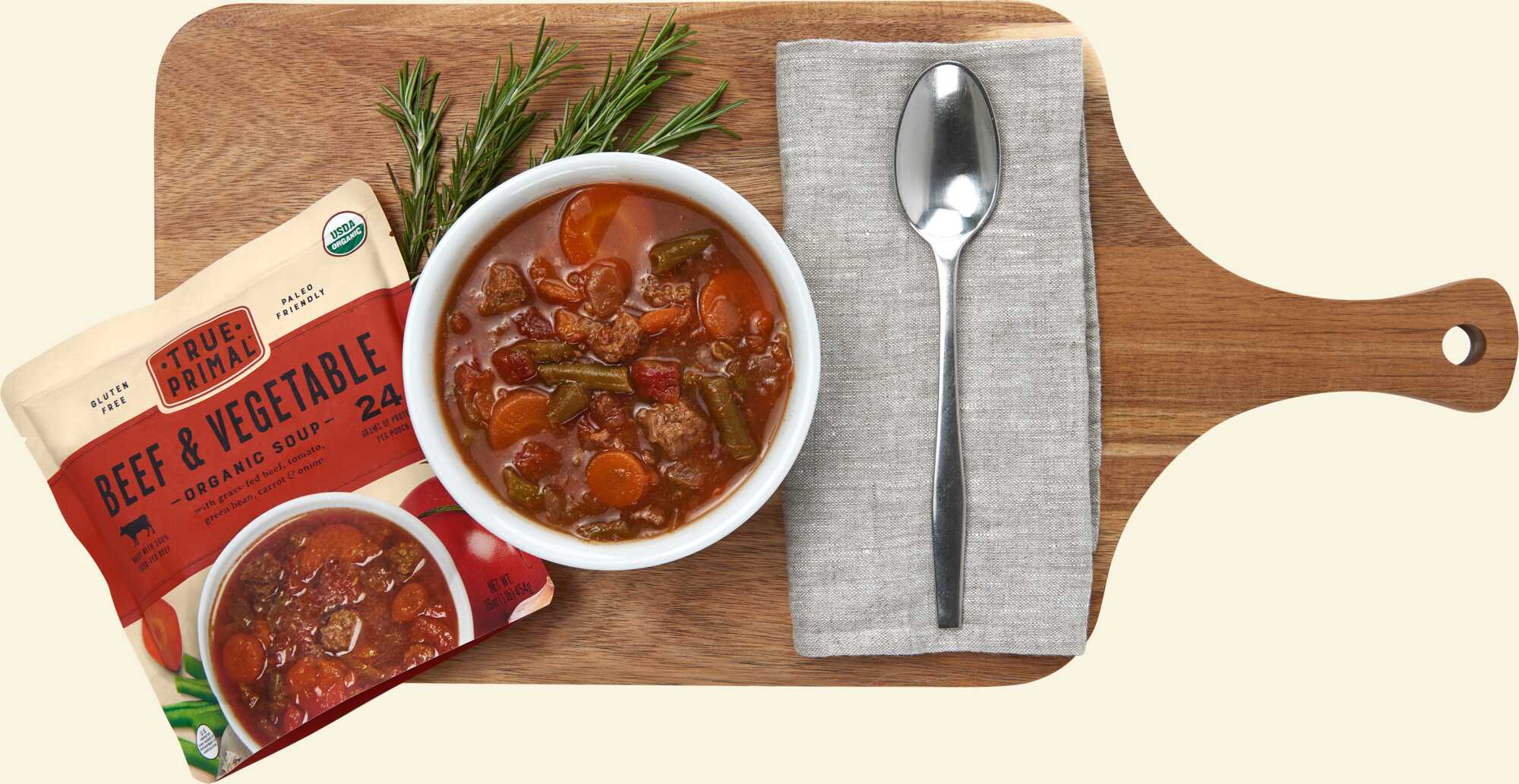 True Primal Beef and Vegetable Organic Soup on cutting board with spoon