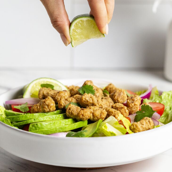 True Primal Grass fed Beef Mini Meatballs in a bowl with a lime being squeezed on top