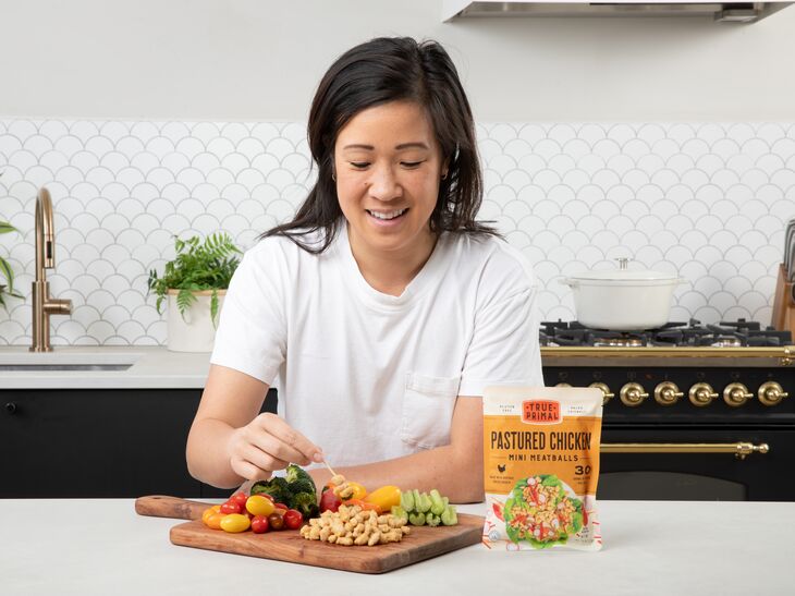 woman eating snack platter with vegetables and True Primal Pastured Chicken Mini Meatballs