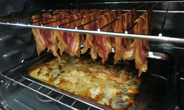 baked bacon hanging from oven rack