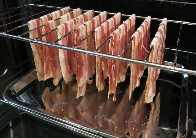 raw bacon hanging from oven rack