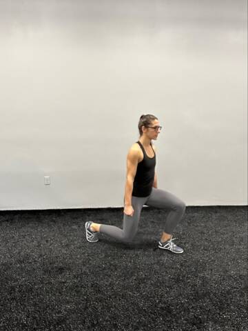 Woman in the bottom of a split squat, both knees are bent to about 90 degrees.