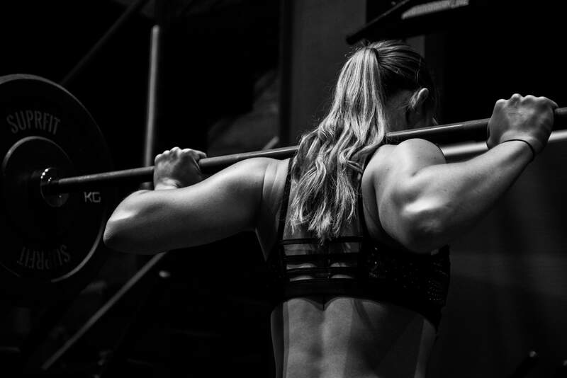 woman lifting barbell on back