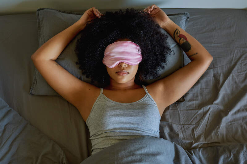 woman wearing a sleeping mask while lying on her bed